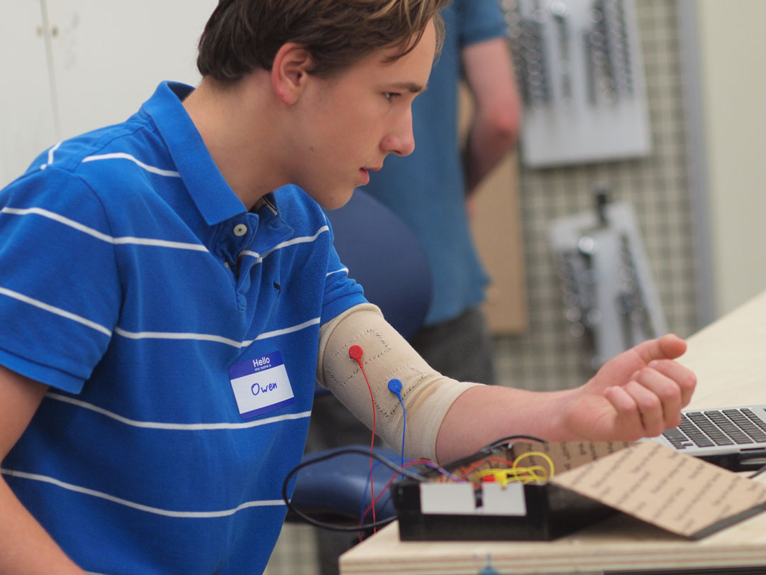 Flexing a communications muscle: Owen Duke, a 10th grader at Phillips Exeter Academy, has been perfecting a biceps cuff to detect intentional twitches. He and a Brown graduate student he met at the makeathon wrote code to translate a muscle twitch into a computer click. Flexing a communications muscle: Owen Duke, a 10th grader at Phillips Exeter Academy, has been perfecting a biceps cuff to detect intentional twitches. He and a Brown graduate student he met at the makeathon wrote code to translate a muscle twitch into a computer click.